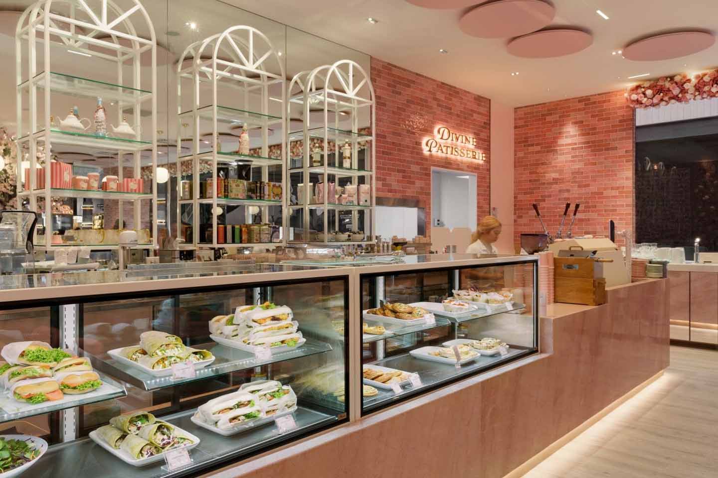 Stylish patisserie interior with warm white commercial lighting illuminating display cabinets, shelving, and counter areas.