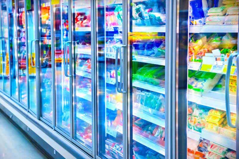 Supermarket refrigerated display cabinets with bright LED shelf lighting improving product visibility across multiple shelves.