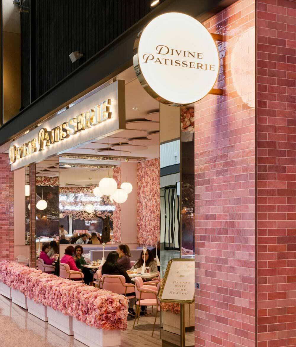 Illuminated Divine Patisserie storefront signage with backlit round sign and glowing channel letter lightbox installed by Display Lighting.