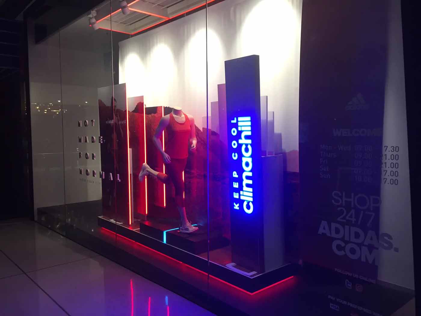 Outdoor shopfront display with illuminated signage and LED strip lighting highlighting a retail window installation
